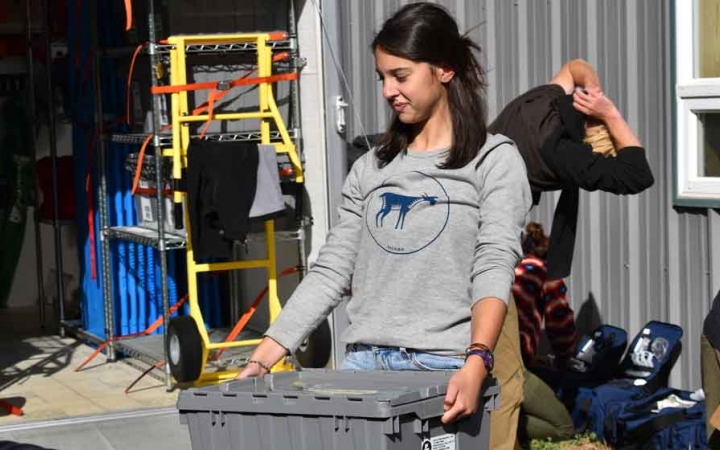 A person carries a plastic crate during a service project with outward bound